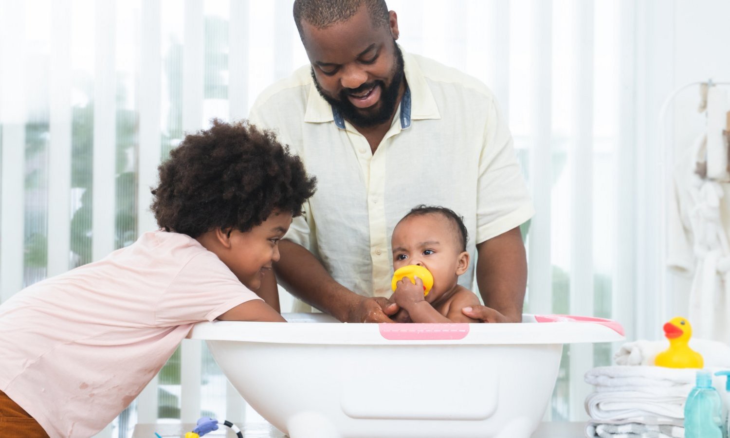 Ein Mann und ein Kind baden ein Baby in der Babybadewanne