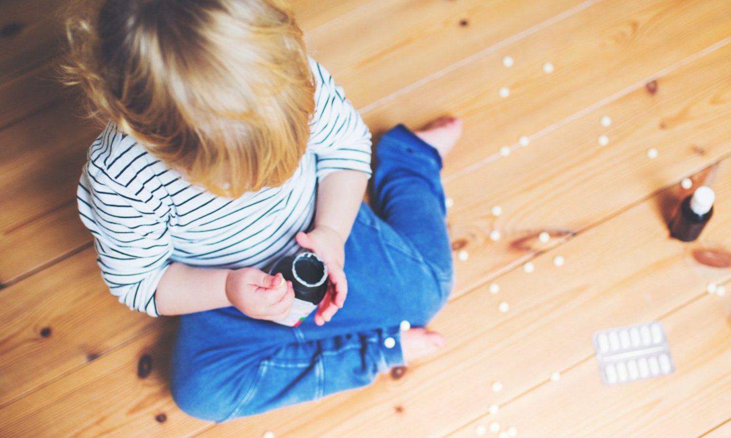Ein Junge sitzt auf dem Holzboden und spielt mit Tabletten