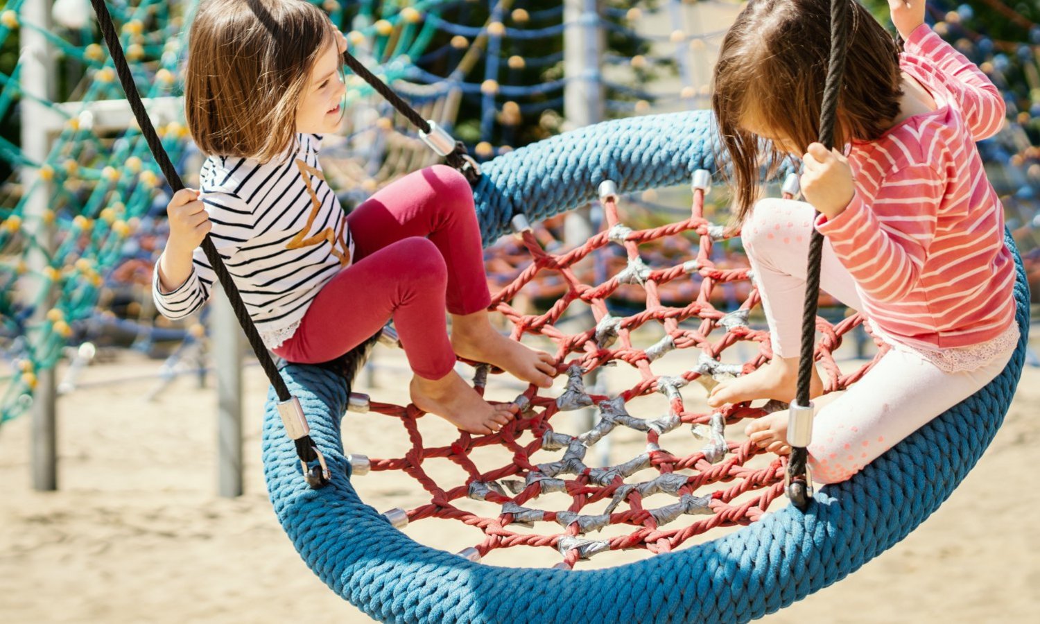 Zwei Kinder schaukeln auf einer Nestschaukel