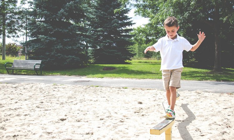 Junge balanciert auf dem Spielplatz auf einem Balken