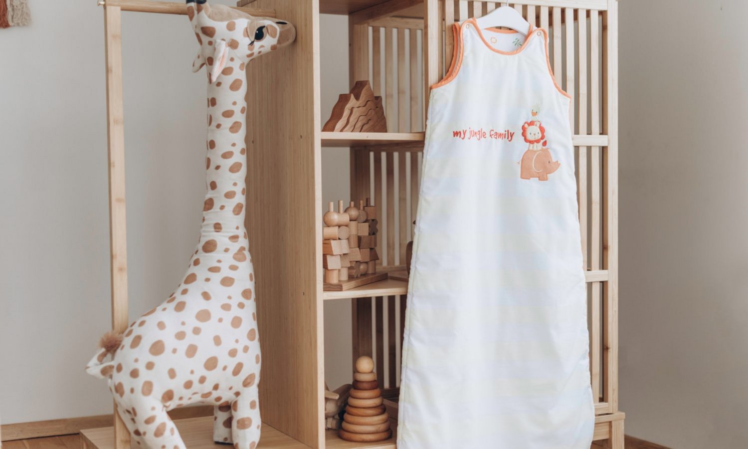 Am Holzregal im Kinderzimmer hängt ein heller Babyschlafsack