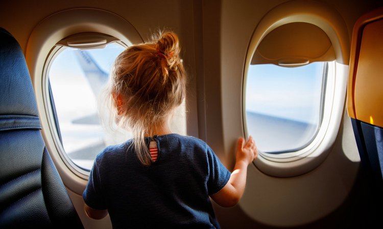 Ein Kleinkind schaut aus dem Fenster eines Flugzeugs