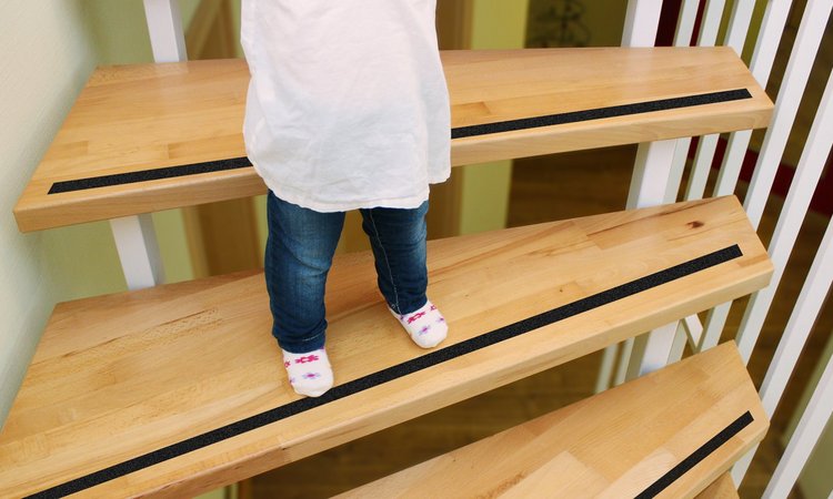 Ein Kind steht auf einer Treppenstufe welche mit Anti-Rutsch-Band gesichert ist.