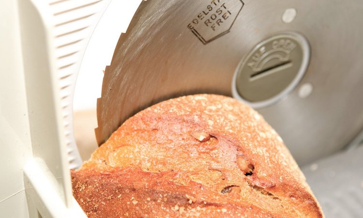 Ein Laib Brot liegt auf einer Brotschneidemaschine