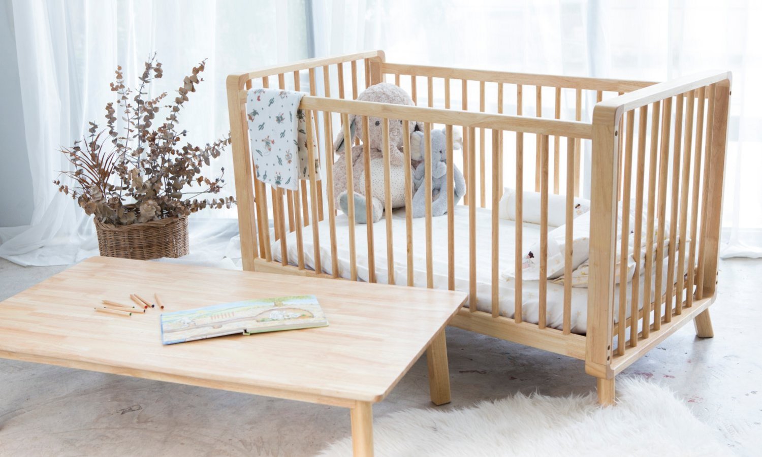 ein Babybett steht neben einem Tisch in einem lichtdurchfluteten Raum