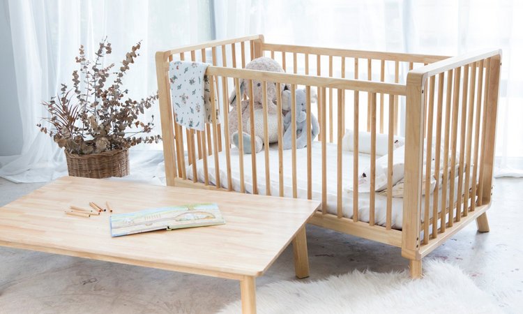 ein Babybett steht neben einem Tisch in einem lichtdurchfluteten Raum