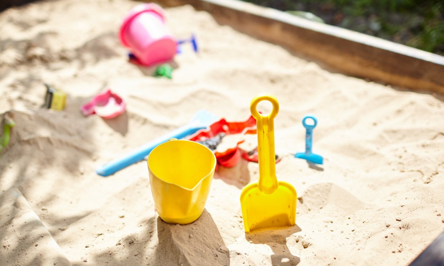 In einem Sandkasten liegt buntes Plastikspielzeug