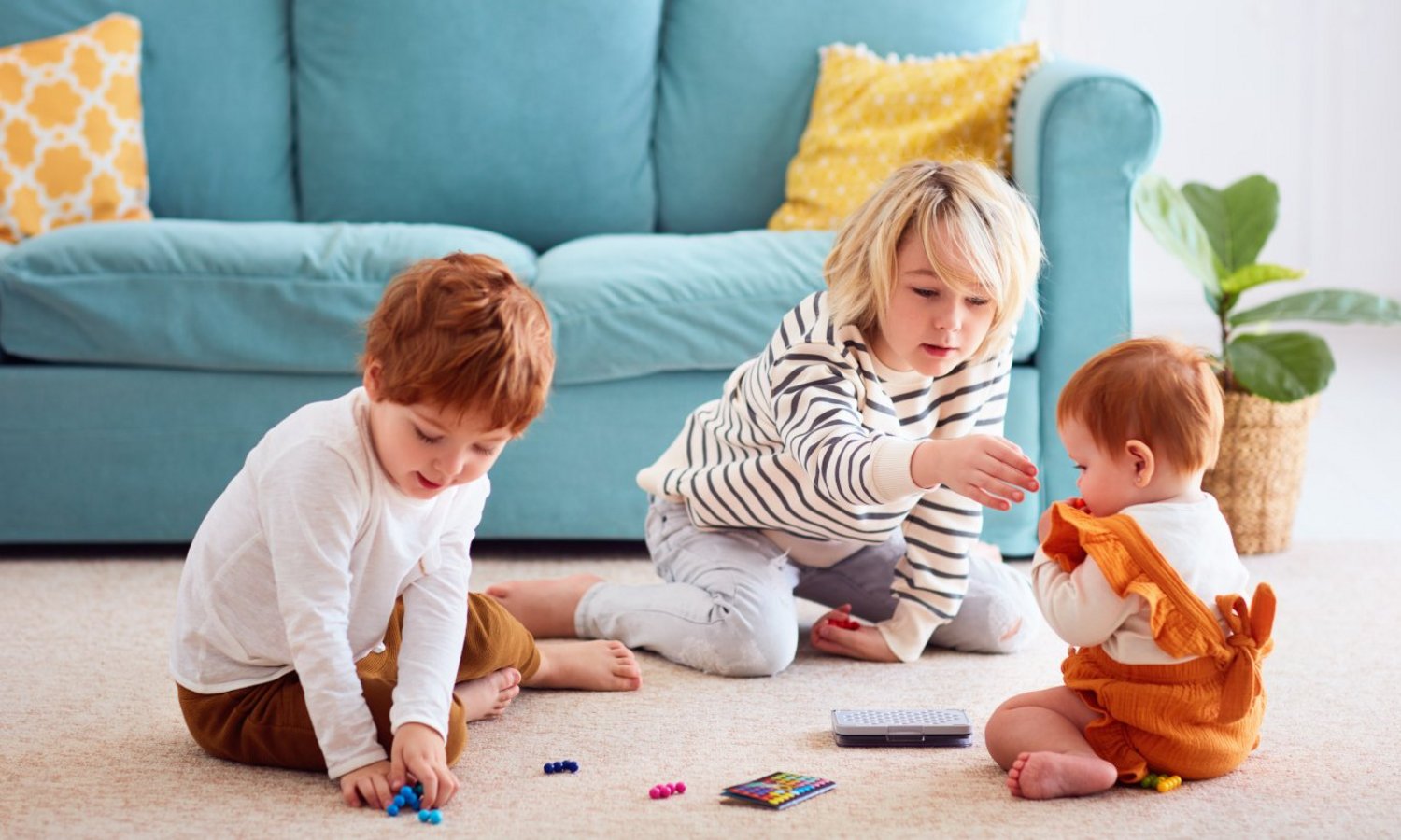 Ein Kind nimmt einem Baby verschluckbare Kleinteile ab