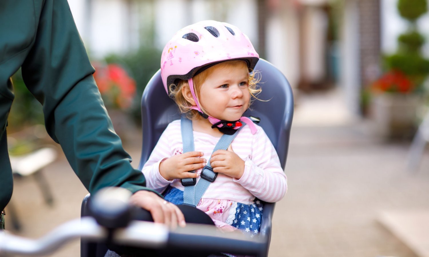 Ein Kleinkind mit Helm sitzt angeschnallt in einem Fahrradkindersitz