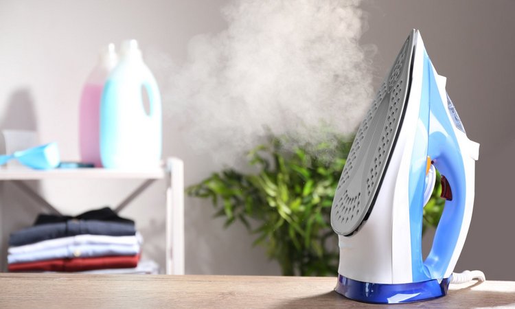 Ein dampfendes Bügeleisen steht aufrecht auf dem Tisch