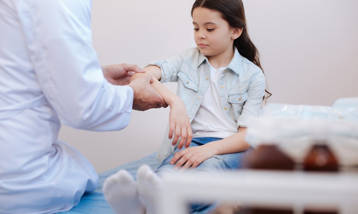 Mädchen wird von einem Arzt am Ellenbogen untersucht