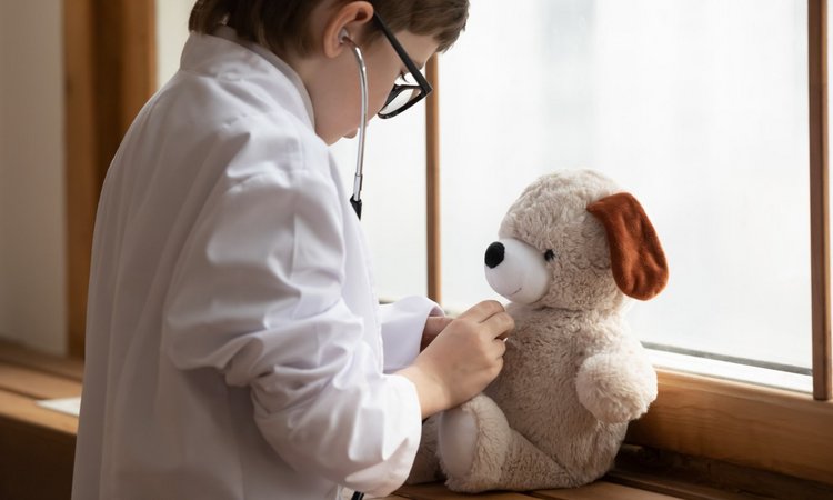 Kind untersucht Stoffteddy mit einem Stethoskop