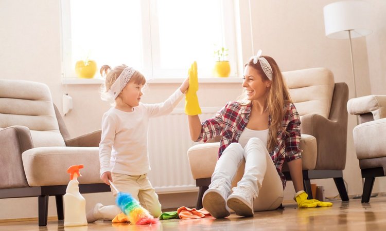 Ein Mädchen und eine Frau putzen gemeinsam und schlagen lächelnd ein