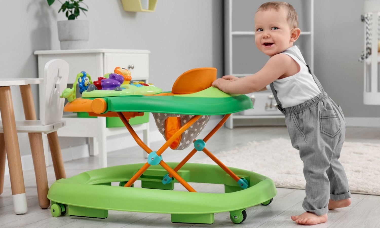 Ein stehendes Baby hält sich am Babywalker fest