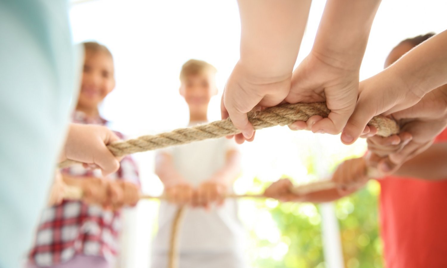 Kinder stehen im Kreis und halten gemeinsam ein Seil fest