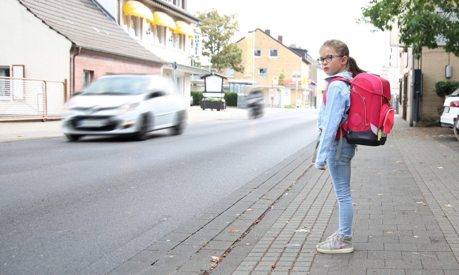 Ein Schulmädchen möchte die befahrene Straßen überqueren