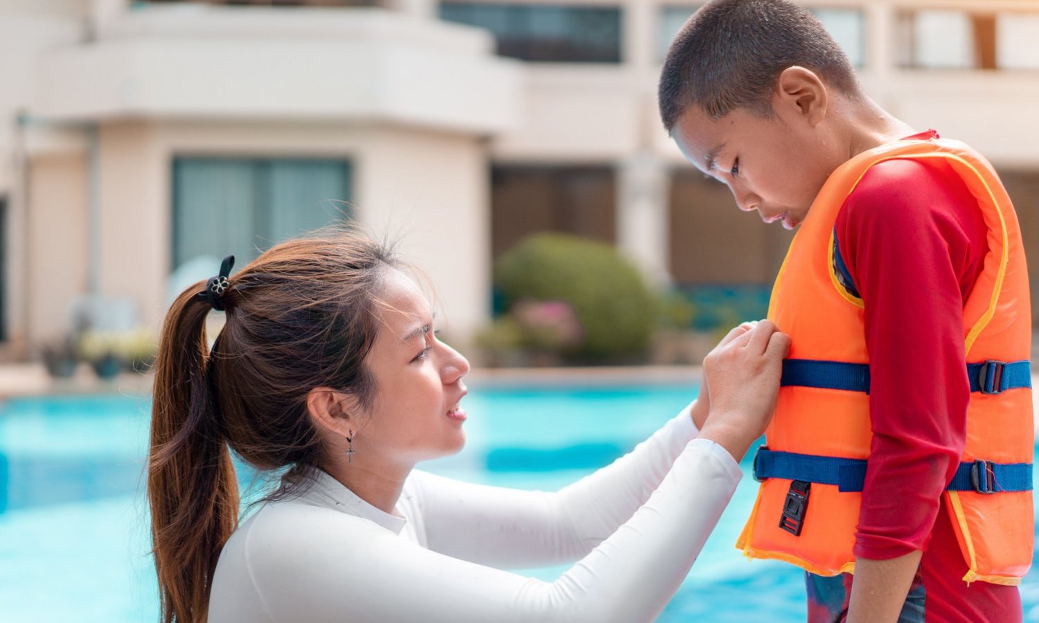 Eine Frau zieht einem Jungen eine Rettungsweste an