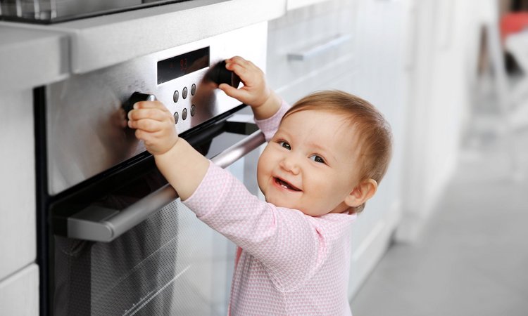 Ein Kleinkind spielt fröhlich an Herdknöpfen