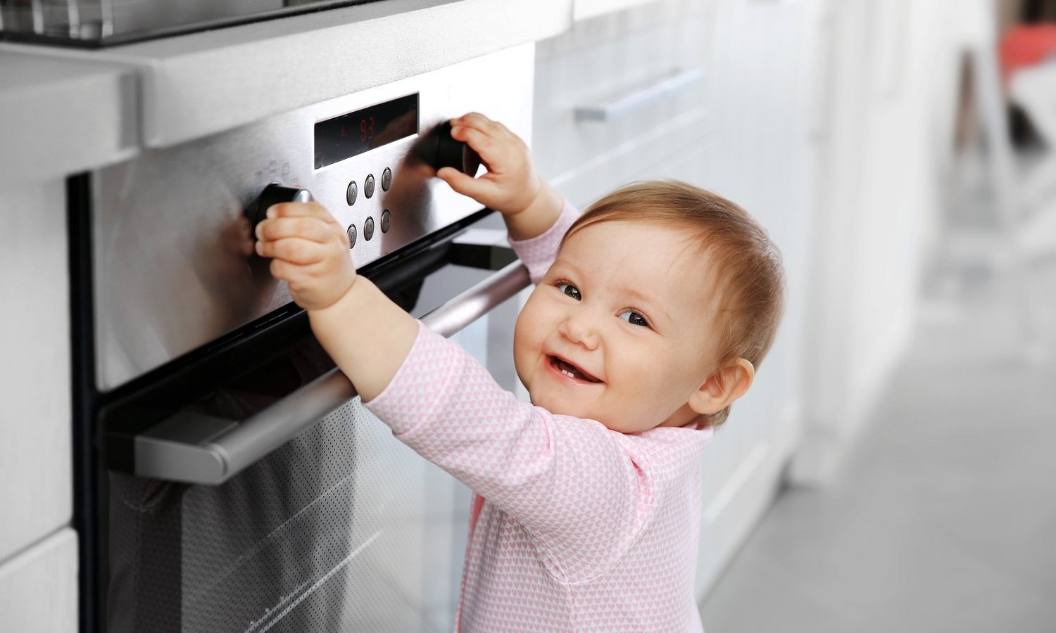 Ein Kleinkind spielt fröhlich an Herdknöpfen