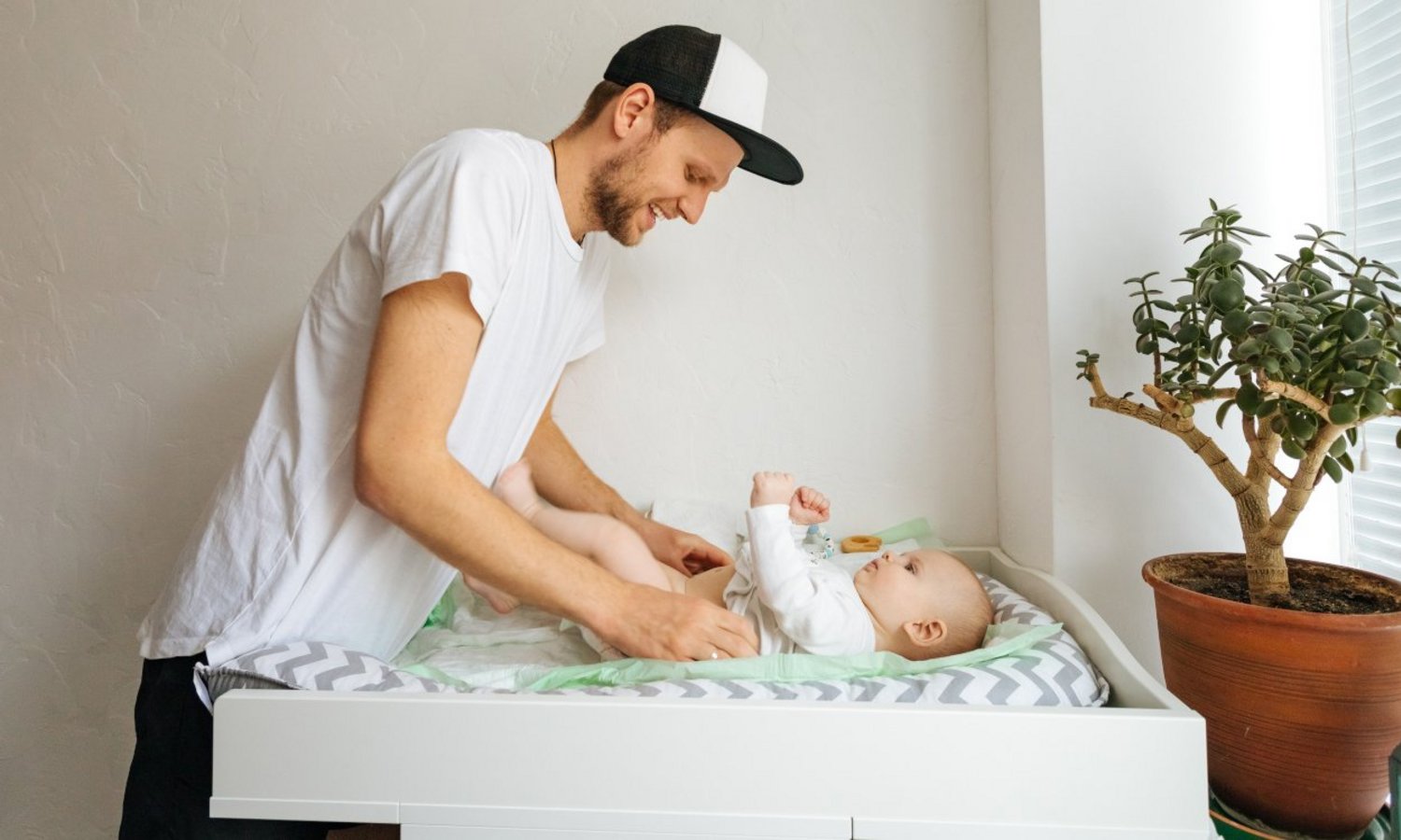 Junger Mann wickelt ein Baby auf dem Wickeltisch