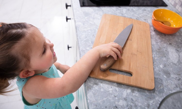 Kind greift nach einem Messer auf der Anrichte