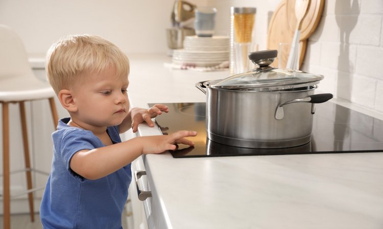 Junge fasst auf die Herdplatte