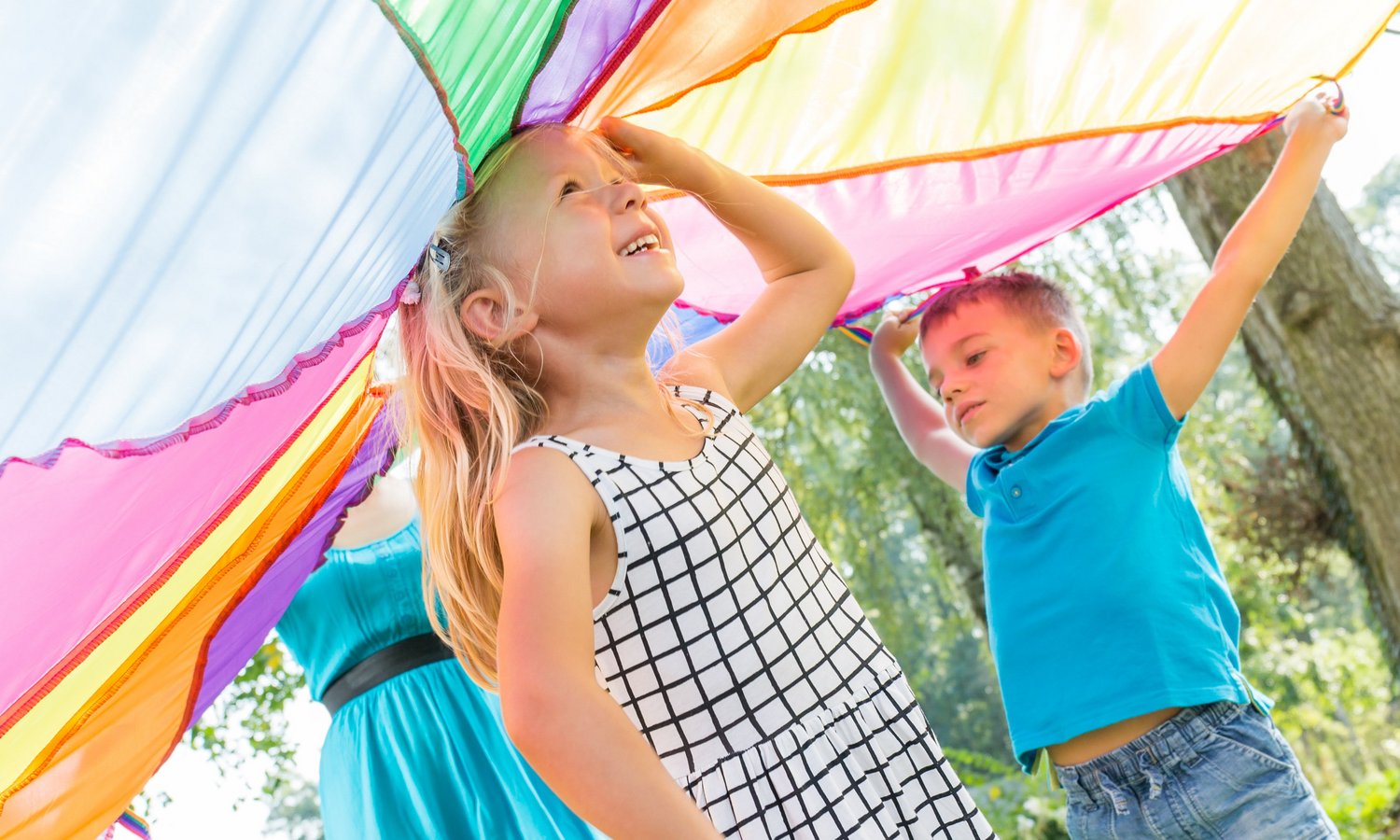 Ein Mädchen steht in der Mitte unter einem von anderen Kindern hochgehaltenen Schwungtuch