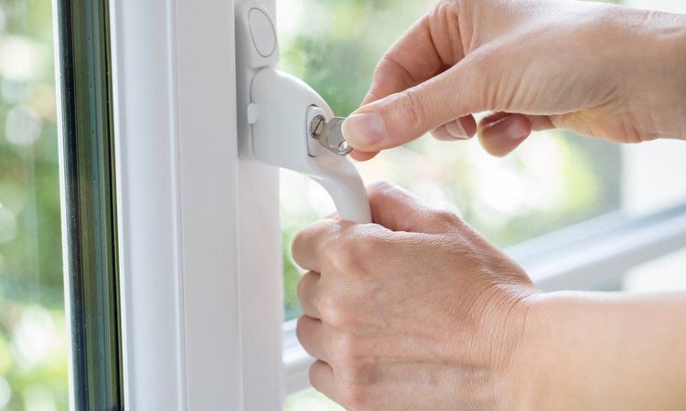 Eine Person dreht den Schüssel der Sicherung am Fenstergriff