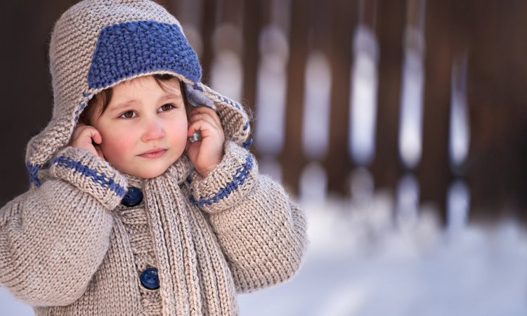 Kind wärmt sich im Schnee die Ohren