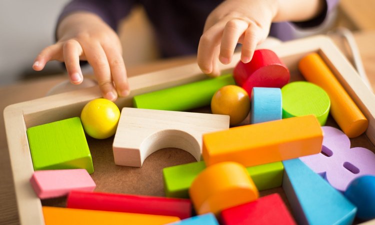 Kinderhände spielen mit Holzklötzen auf einem Holzbrett