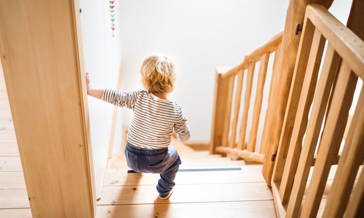 Ein kleines Kind geht alleine die Holztreppe hinunter