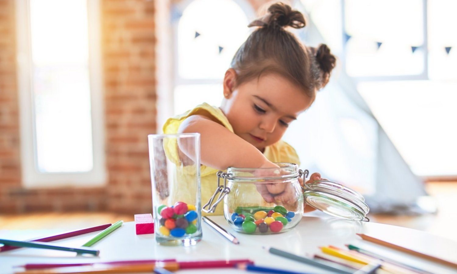 Kind greift nach bunten Dragees im Glas