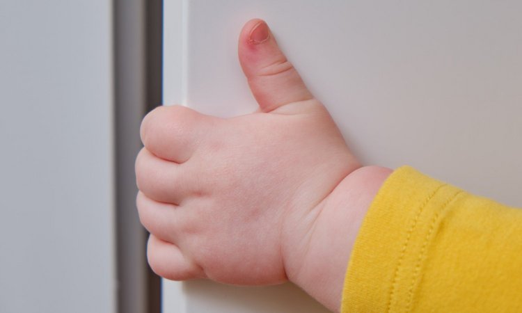 Kleinkind quetscht sich die Finger in einer Tür