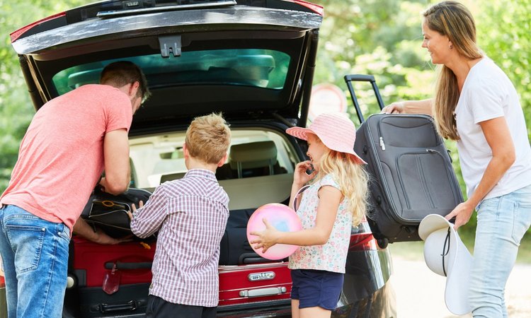 Eine Familie packt den Kofferraum des Autos für den Urlaub