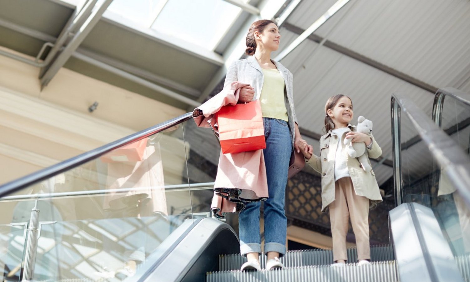 Eine Frau und ein Kind betreten die Rolltreppe nach unten